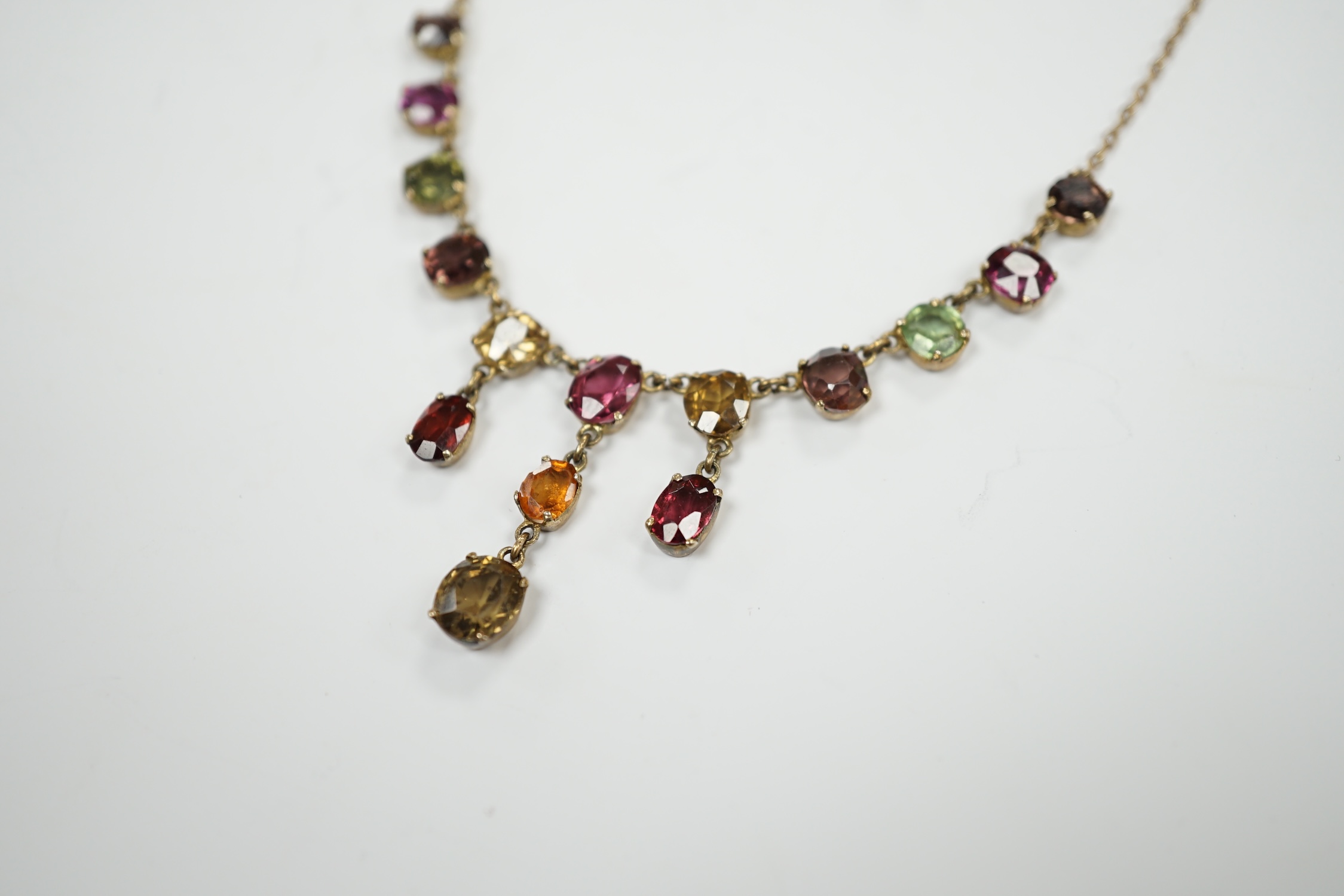 A yellow metal and multi gem set drop necklace, set with oval cut stones including tourmaline and hessonite garnet, 46cm, gross weight 6.6 grams.
